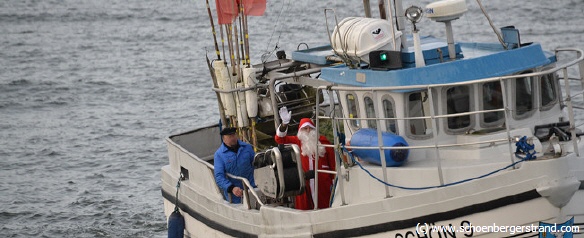 Weihnachtsmann landet an der Seebrücke mit Fischerboot